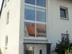 Haustür in weiß mit Lichtausschnitt und Glas-Seitenteil und Fensterfront vor dem Treppenhaus