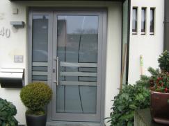Milchglas-Haustür mit Ausschnitten und grauem Rahmen und Seitenteil 