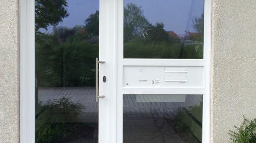 Glashaustür mit weißem Rahmen und breitem Seitenteil mit Briefkasten- und Klingelanlage