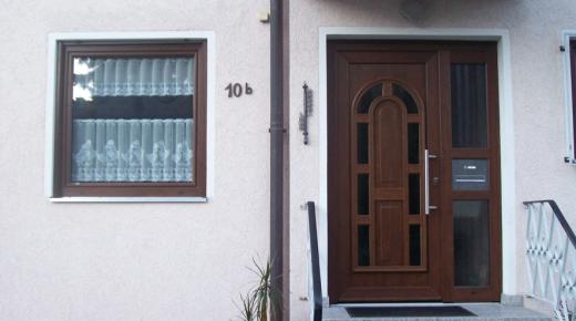 Holzhaustür mit acht im Rundbogen angeordneten Lichtausschnitten und Glas-Seitenteil mit Briefkastenschlitz
