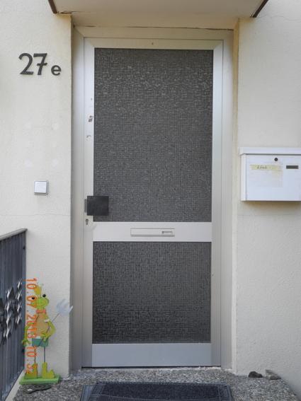 Alte Haustür mit silbernem Rahmen und zwei Glasausschnitten 