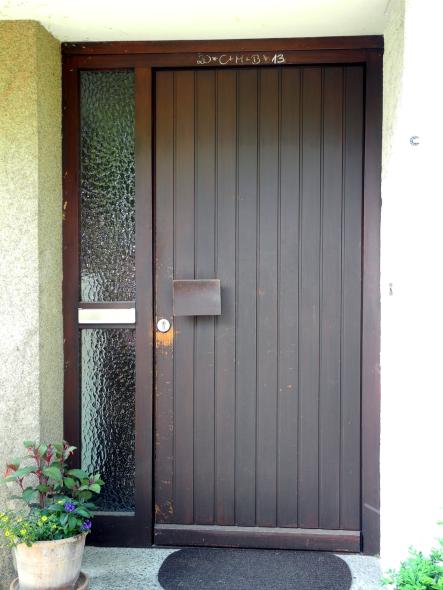 Alte Holzhaustür mit vertikalen Dielen und Glas-Seitenteil mit Briefkastenschlitz 